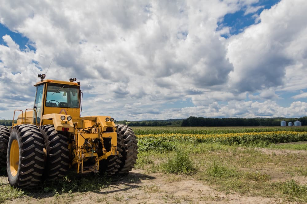 Un "tracteur enjambeur" rouge moderne travaillant entre les rangées d'un vignoble, illustrant la mécanisation précise de la viticulture